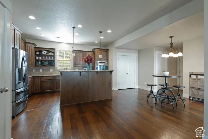 Wood-finish flooring throughout, recessed lighting, and a kitchen island with pendant lighting