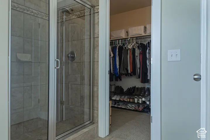 Tiled shower enclosure with a glass door and an adjacent walk-in closet