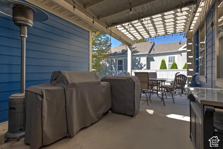 Covered patio featuring a slatted pergola, concrete flooring, and blue siding