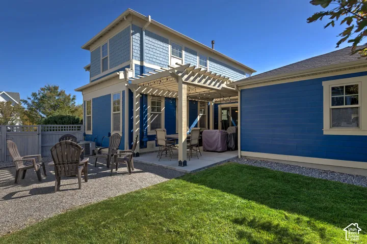 Expansive backyard featuring a manicured lawn, gravel patio area, and a pergola-covered concrete patio