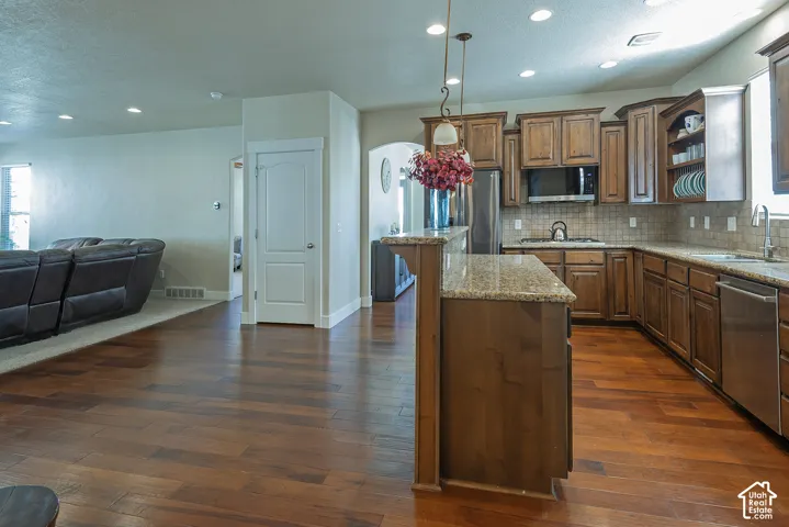 Hardwood-finish flooring throughout, kitchen with wood cabinetry, granite countertops, tile backsplash, and stainless steel appliances