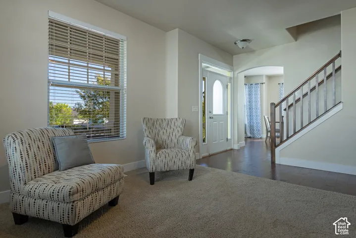Entryway featuring a solid wood door with an arched glass insert, wood-finish flooring, and a carpeted area
