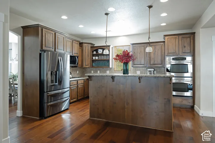 Kitchen featuring wood-finish flooring, recessed lighting, wood cabinetry, stone countertops, and stainless steel appliances