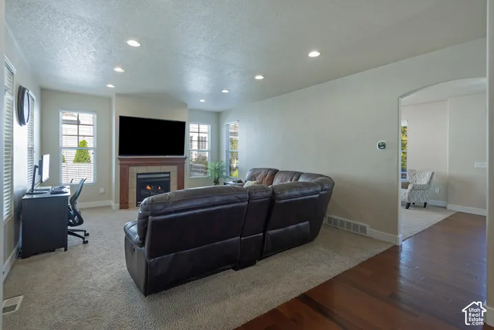 Recessed lighting, fireplace with tile surround, wood mantel, multiple windows, and a carpeted floor