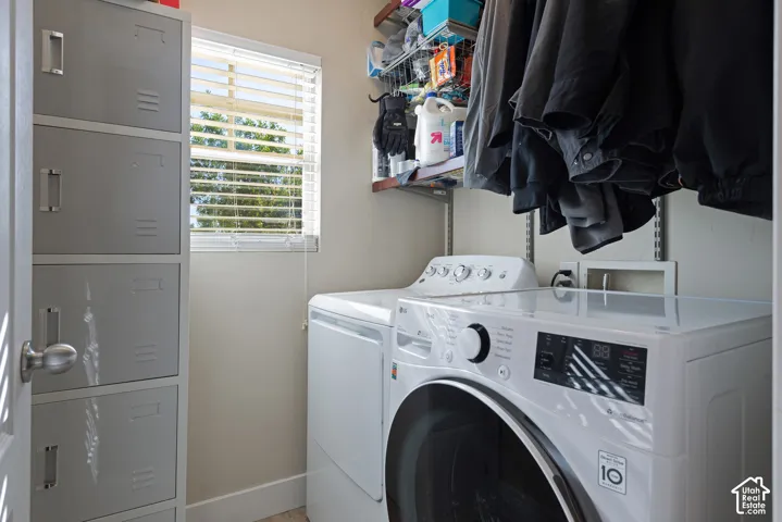 Laundry area featuring a window with blinds, a clothes washer and dryer, and built-in shelving