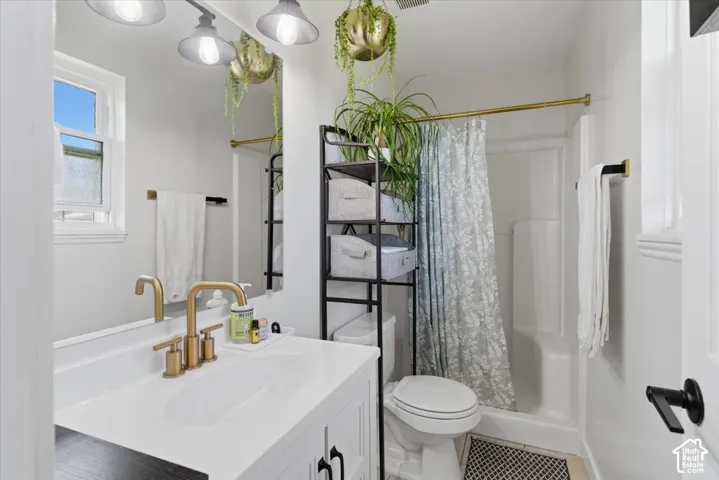 Bathroom featuring a white vanity with gold-finish fixtures, a single-pane window, and a shower with an integrated tub