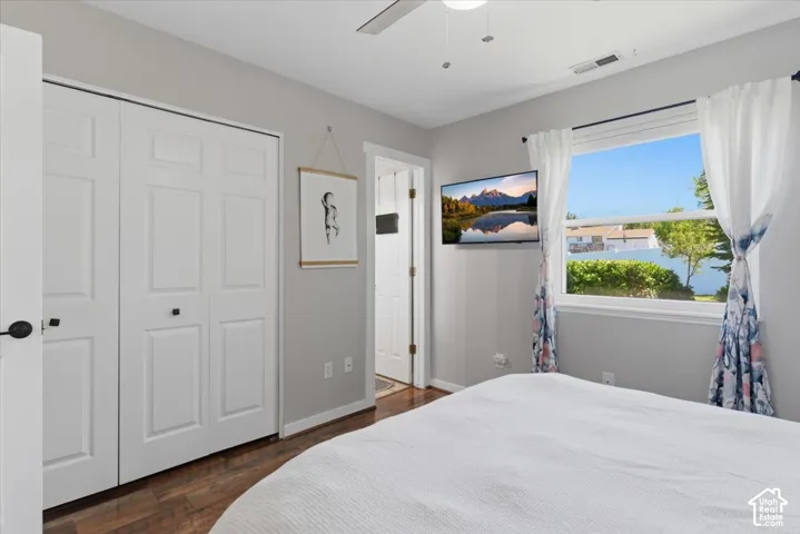 Hardwood-finish flooring, white bi-fold closet doors, light gray wall tones, and a ceiling fan with integrated lighting