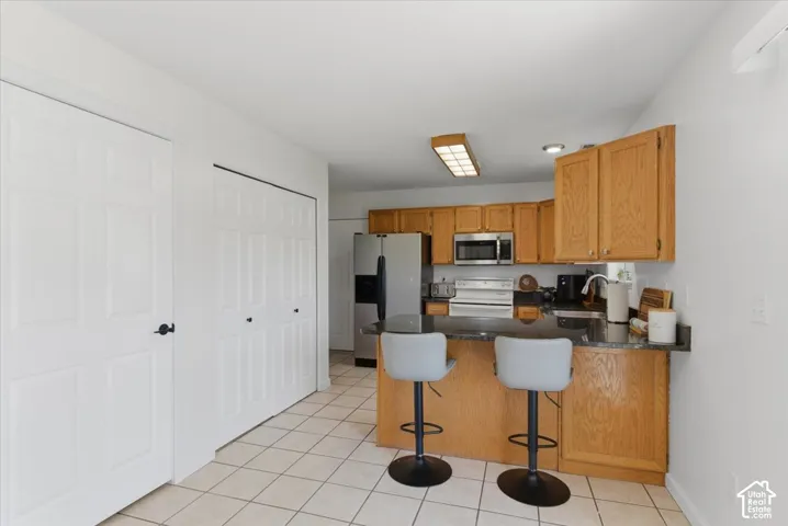 Kitchen with wood-finish cabinetry, stainless steel appliances, granite-look countertops, and tile flooring