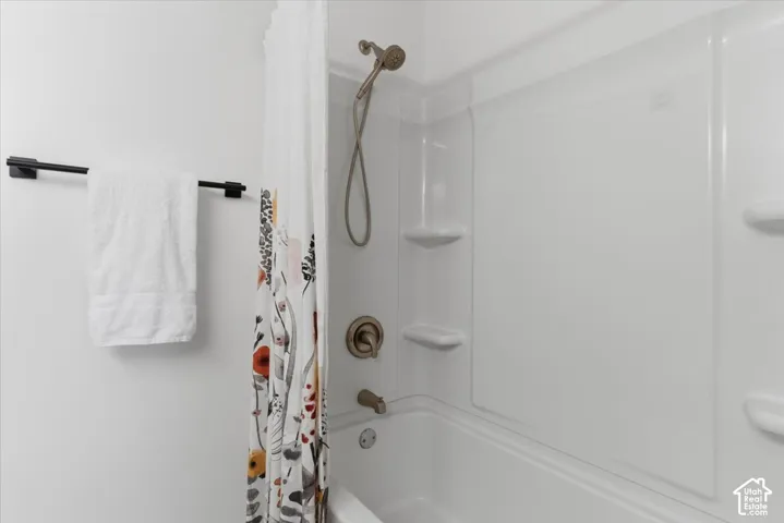 White fiberglass tub and shower combination with integrated shelving