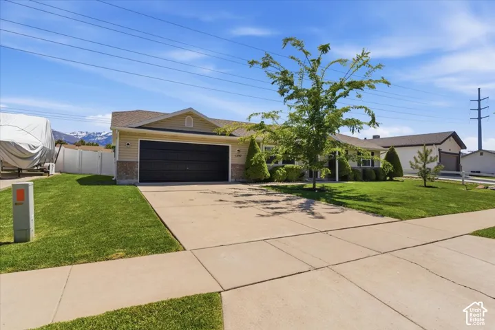 Ranch-style exterior with a two-car garage, concrete driveway, and a manicured lawn