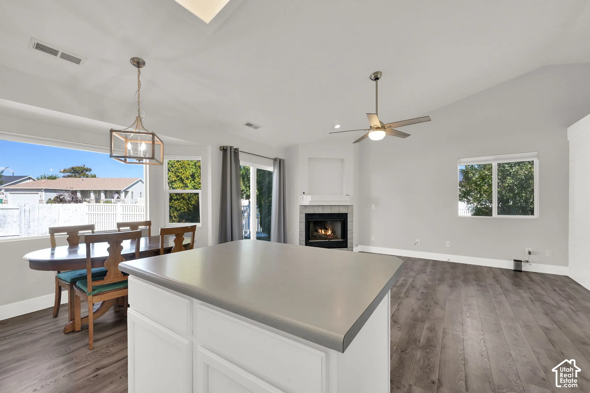 Kitchen island with solid surface countertop, vaulted ceilings, wood-finish flooring, and a fireplace with a mantel