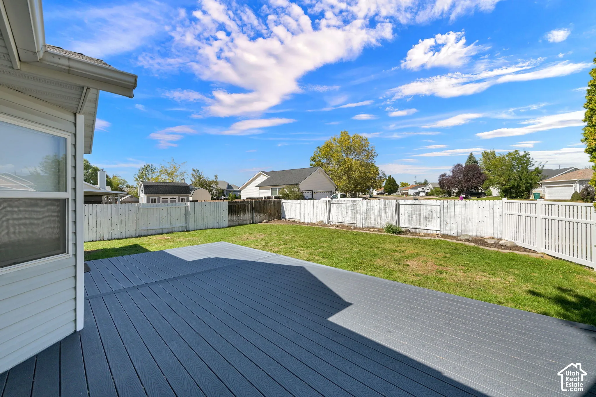 Expansive backyard featuring a composite deck, green lawn, and privacy fencing