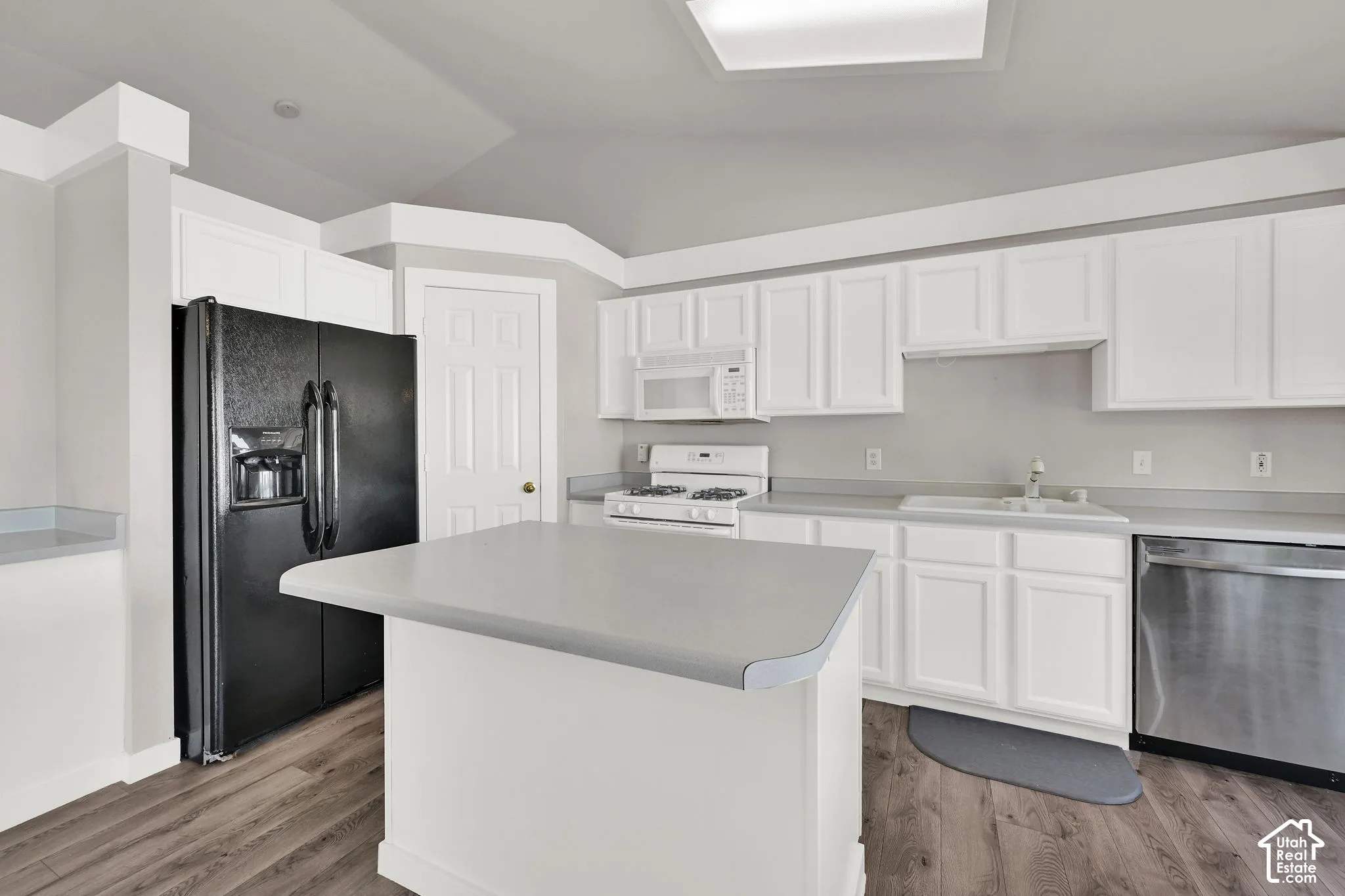 Kitchen featuring white cabinetry, a central island with wood-finish flooring, a stainless steel dishwasher, and a white gas range