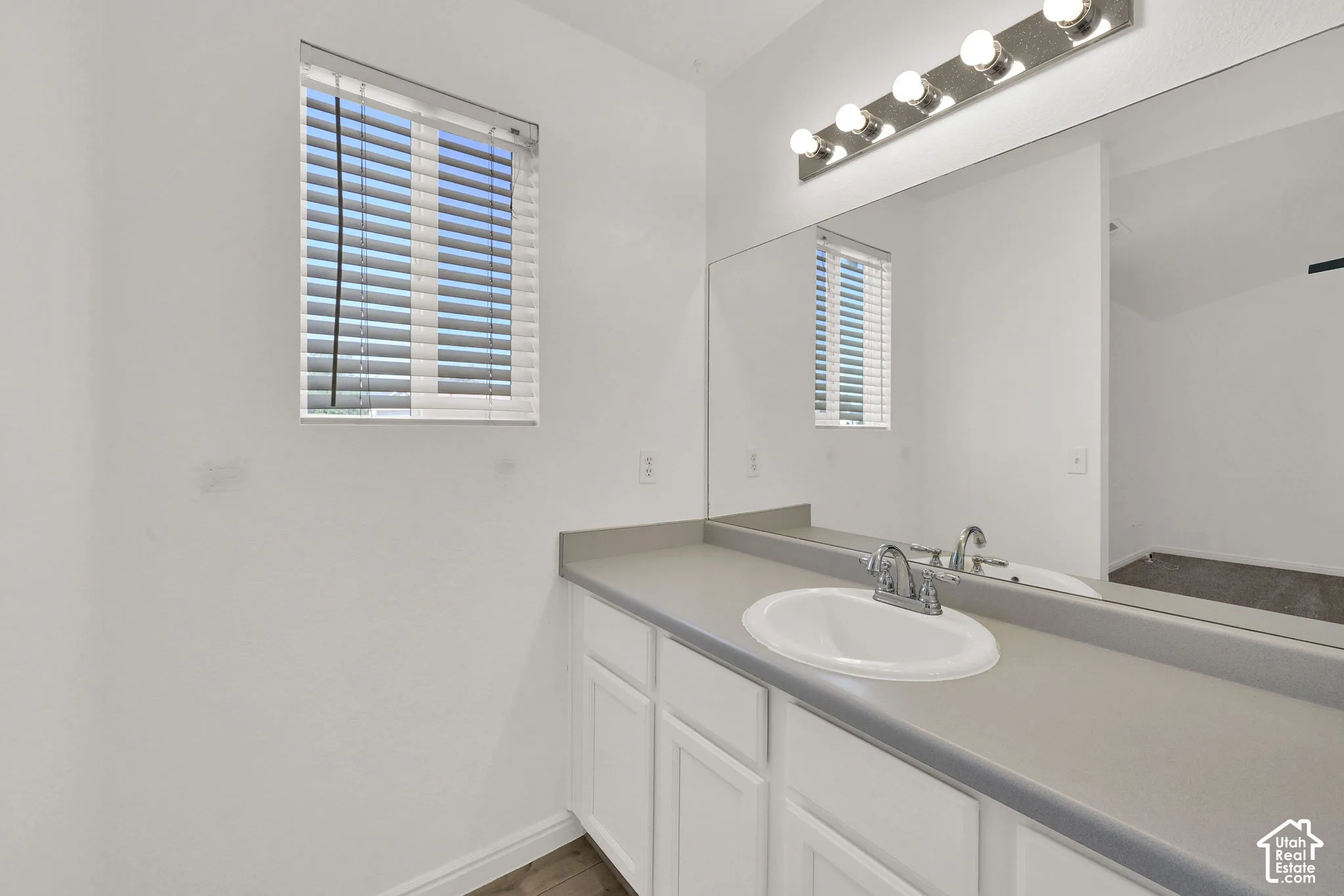 Primary Bathroom Vanity with an integrated sink, polished chrome faucet, and white cabinetry
