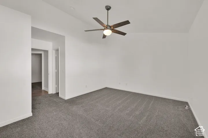 Primary Bedroom with vaulted ceiling with a ceiling fan, neutral wall paint, and gray carpeting