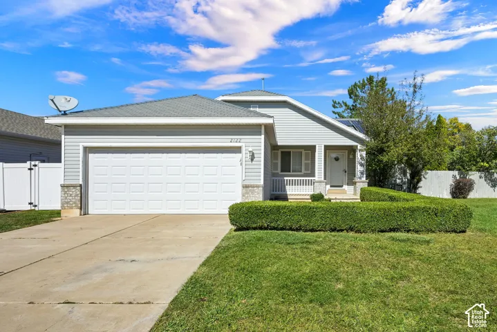 Light gray siding exterior with a white paneled garage door, a covered front porch, and a concrete driveway