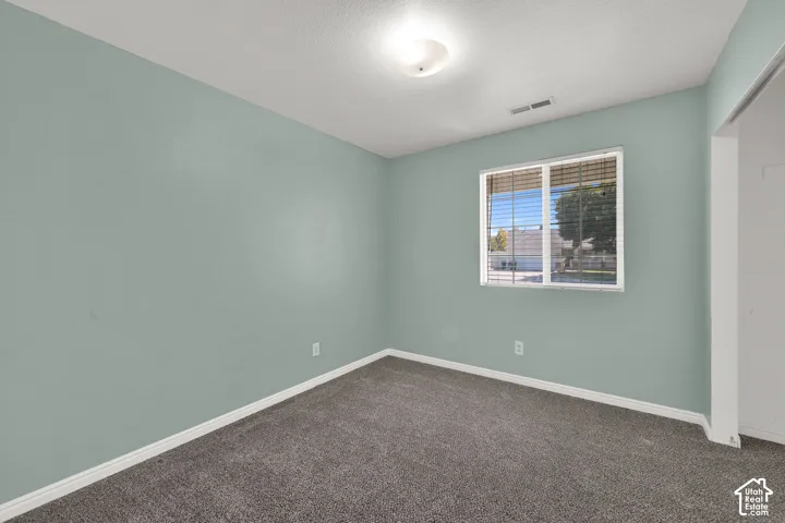 Bedroom, light wall paint, ceiling-mounted light fixture, and dark gray carpeting