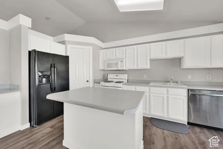 Kitchen featuring white cabinetry, a central island with wood-finish flooring, a stainless steel dishwasher, and a white gas range