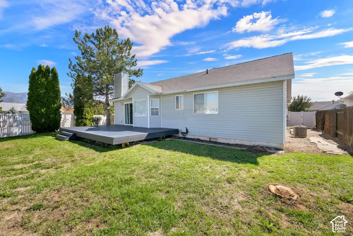 Expansive backyard featuring a large composite deck, mature trees, and full fence
