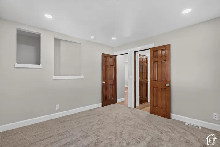 Recessed lighting, wood-finish doors, built-in shelving, light gray wall paint, and carpeting