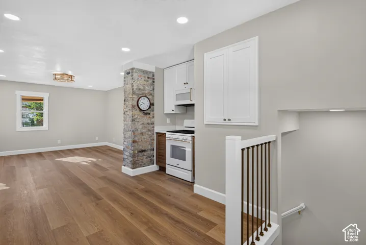 Spacious open concept room featuring wood-finish flooring, recessed lighting, and a stone-clad architectural column