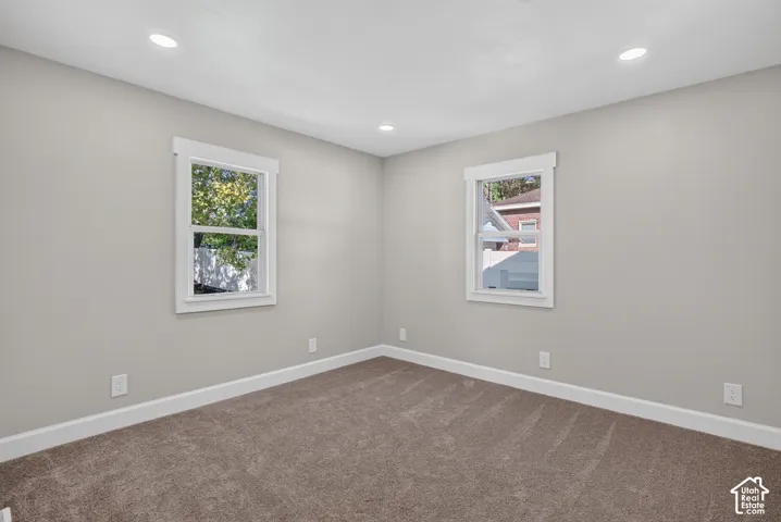 Neutral tone wall paint, recessed lighting, white window trim, and carpeted flooring