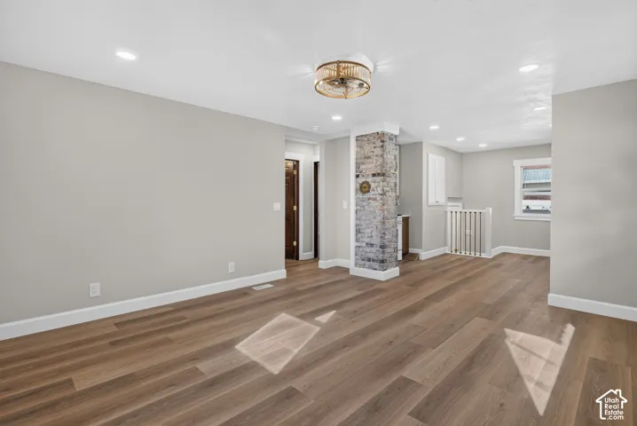 Wood-finish flooring throughout, recessed lighting, and a decorative stone-clad column