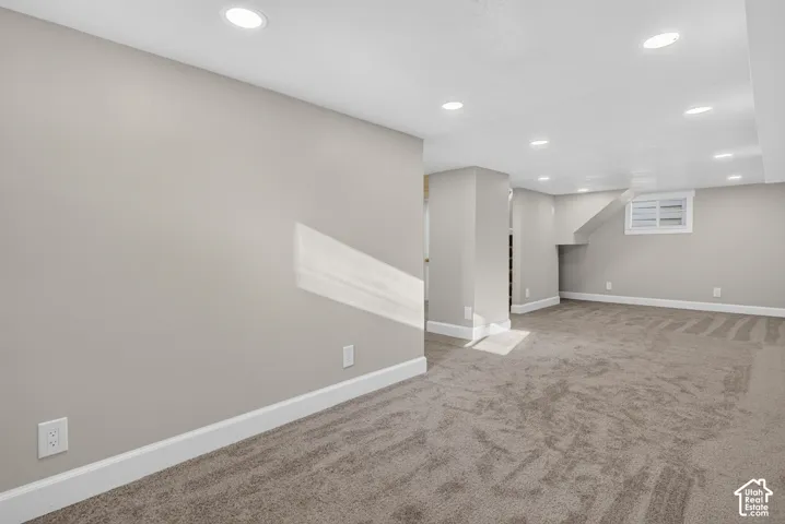 Recessed ceiling lighting illuminates the carpeted flooring and light-toned walls