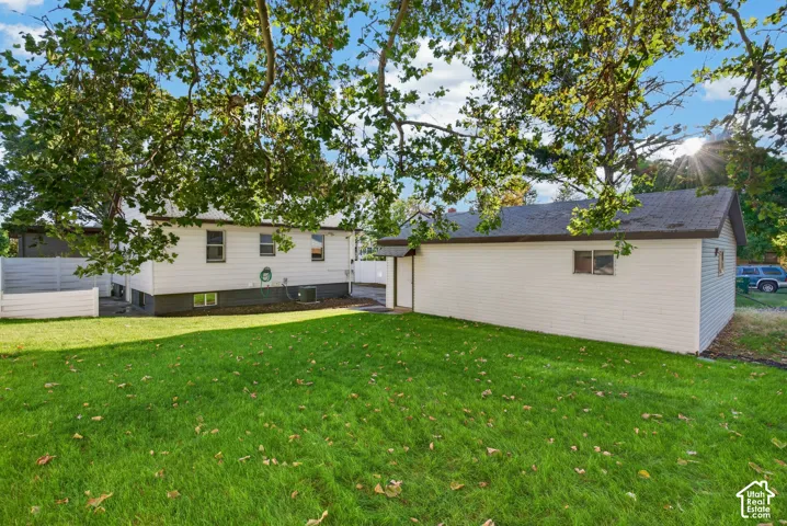 Expansive grassy area with a detached garage structure and an additional outbuilding featuring white siding