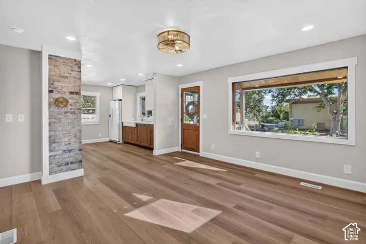 Wood-finish flooring, exposed brick accent wall, recessed lighting, large picture window, and a decorative ceiling fixture