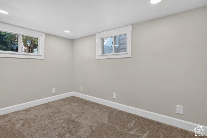 Neutral-toned carpeting, light-colored walls, white trim, recessed lighting, and dual windows