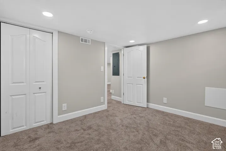 Neutral tone wall finish, recessed ceiling lighting, carpet flooring, interior panel doors, and white trim work