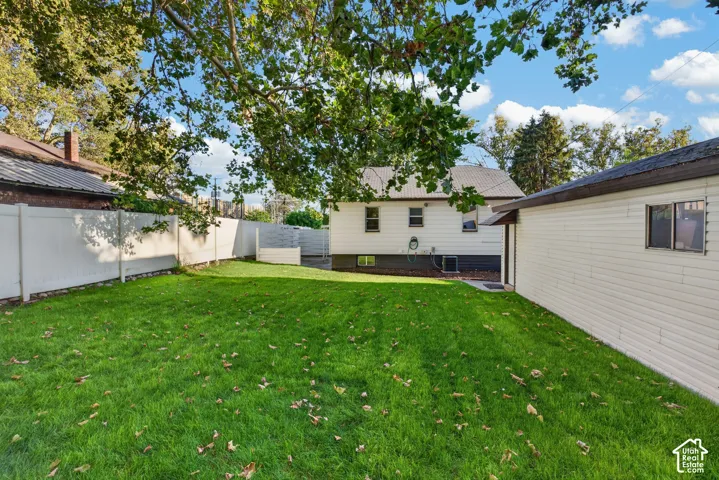 Expansive backyard featuring a manicured lawn, mature shade trees, and fenced perimeter