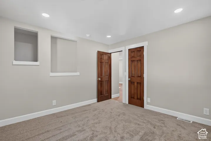 Recessed lighting, wood-finish panel doors, light-toned carpeting, and neutral wall paint