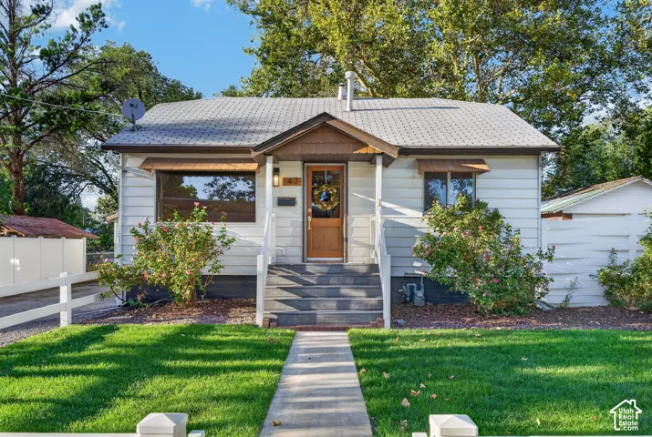 White horizontal siding exterior with a peaked entry porch and a wood-panel front door