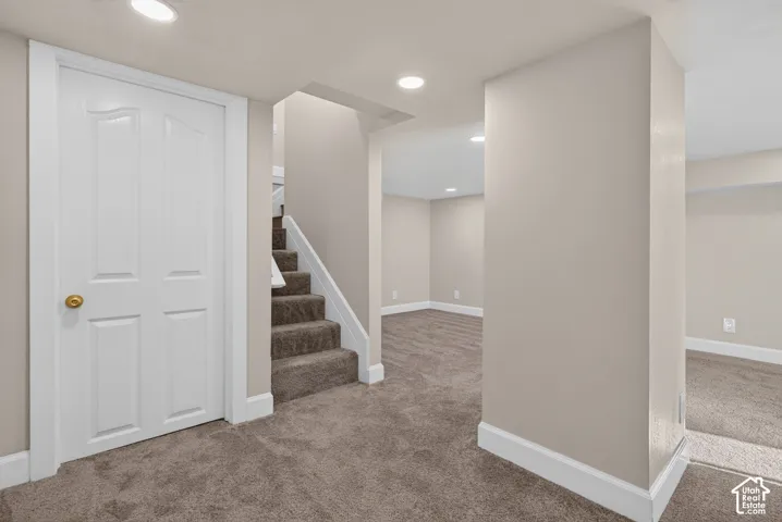Neutral wall paint throughout, recessed ceiling lighting, textured carpeting, white trim, and a paneled interior door