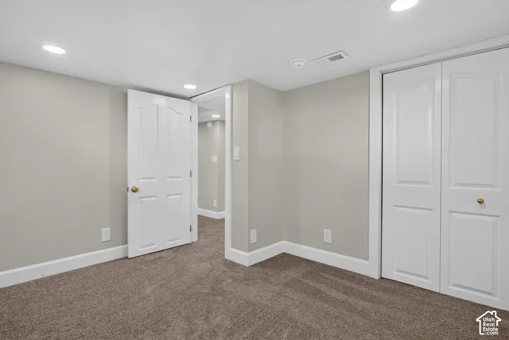 Recessed lighting, neutral wall paint, white trim, carpeted flooring, and a white bi-fold closet door