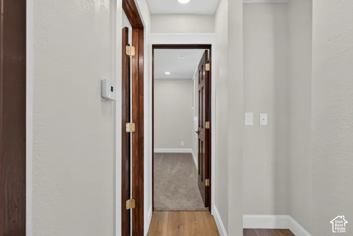 Hallway featuring wood-finish flooring, light neutral wall paint, white trim, and recessed lighting