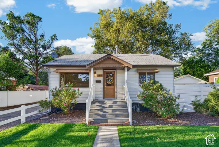Exterior featuring white siding, a covered entry, a gabled roofline, and a paved walkway
