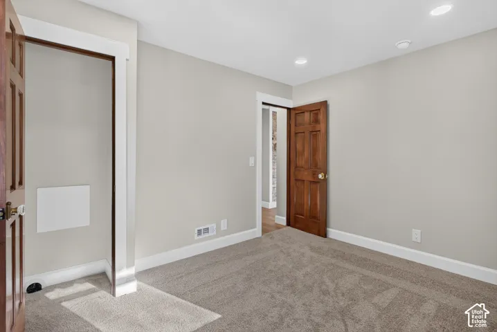 Neutral wall paint, recessed lighting, wood-finish doors, and carpet flooring