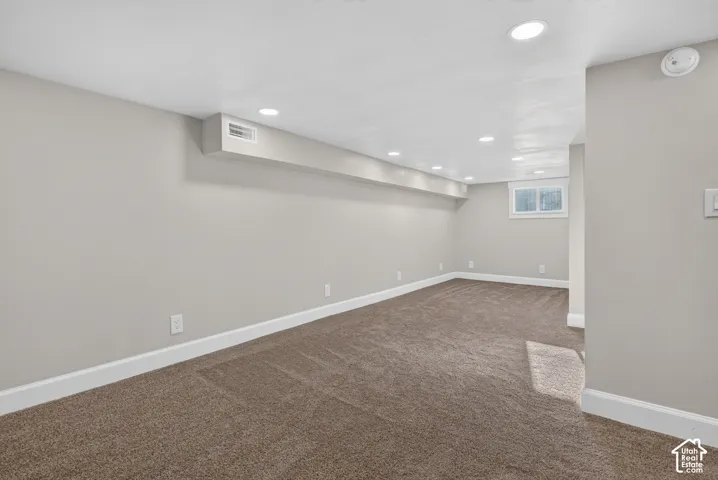 Recessed lighting, light-toned carpeting, neutral wall finishes, and a window for natural light