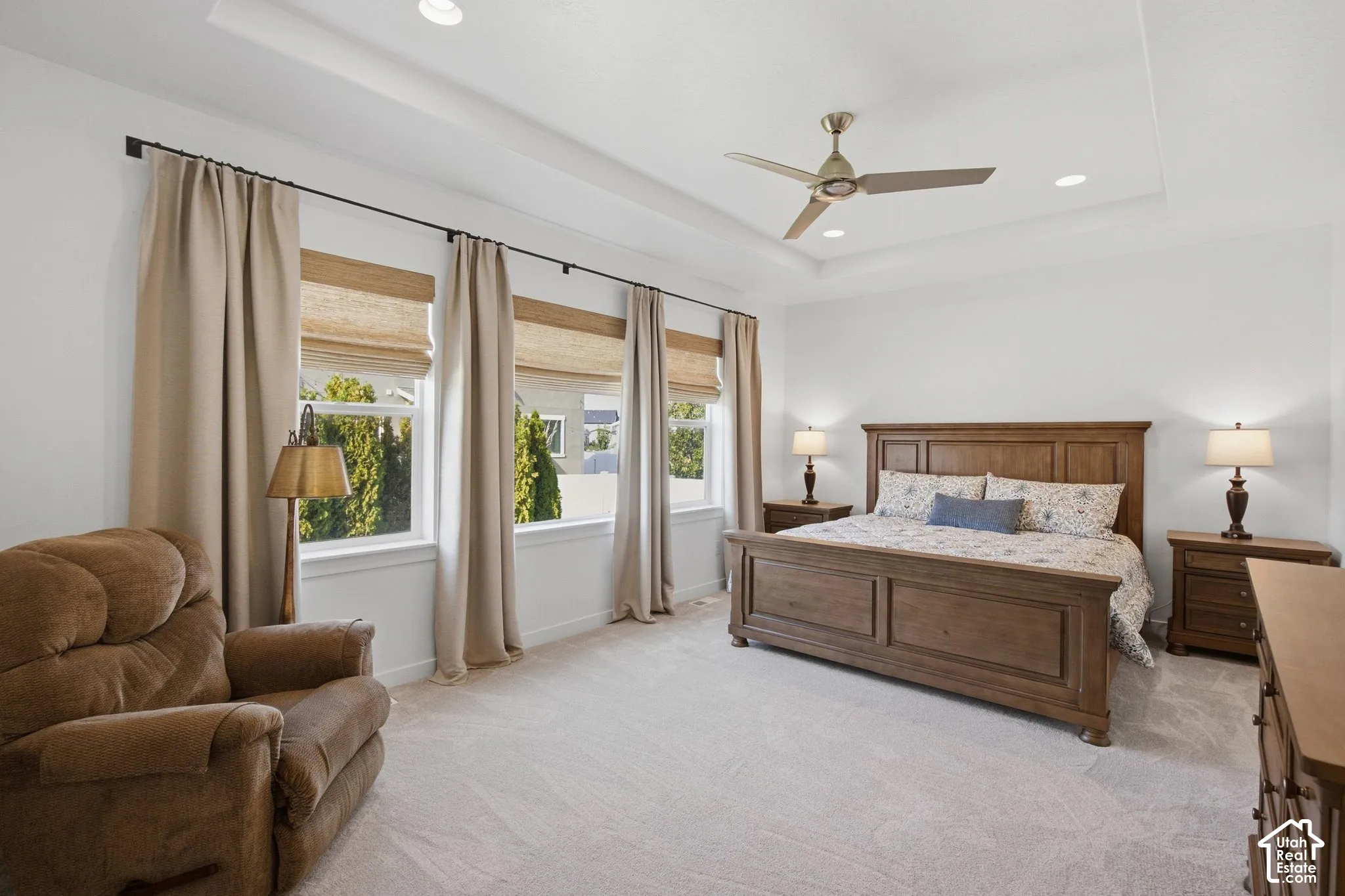 Recessed lighting, tray ceiling, ceiling fan, and multiple windows with blinds