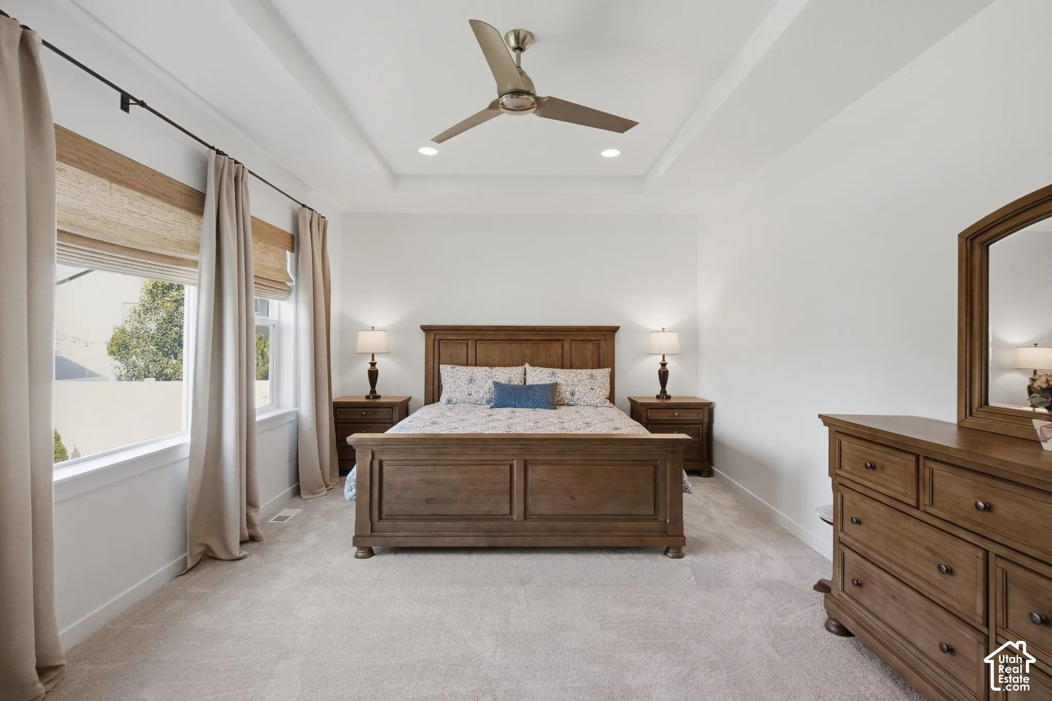 Recessed lighting, ceiling fan, and tray ceiling complement the neutral wall finishes