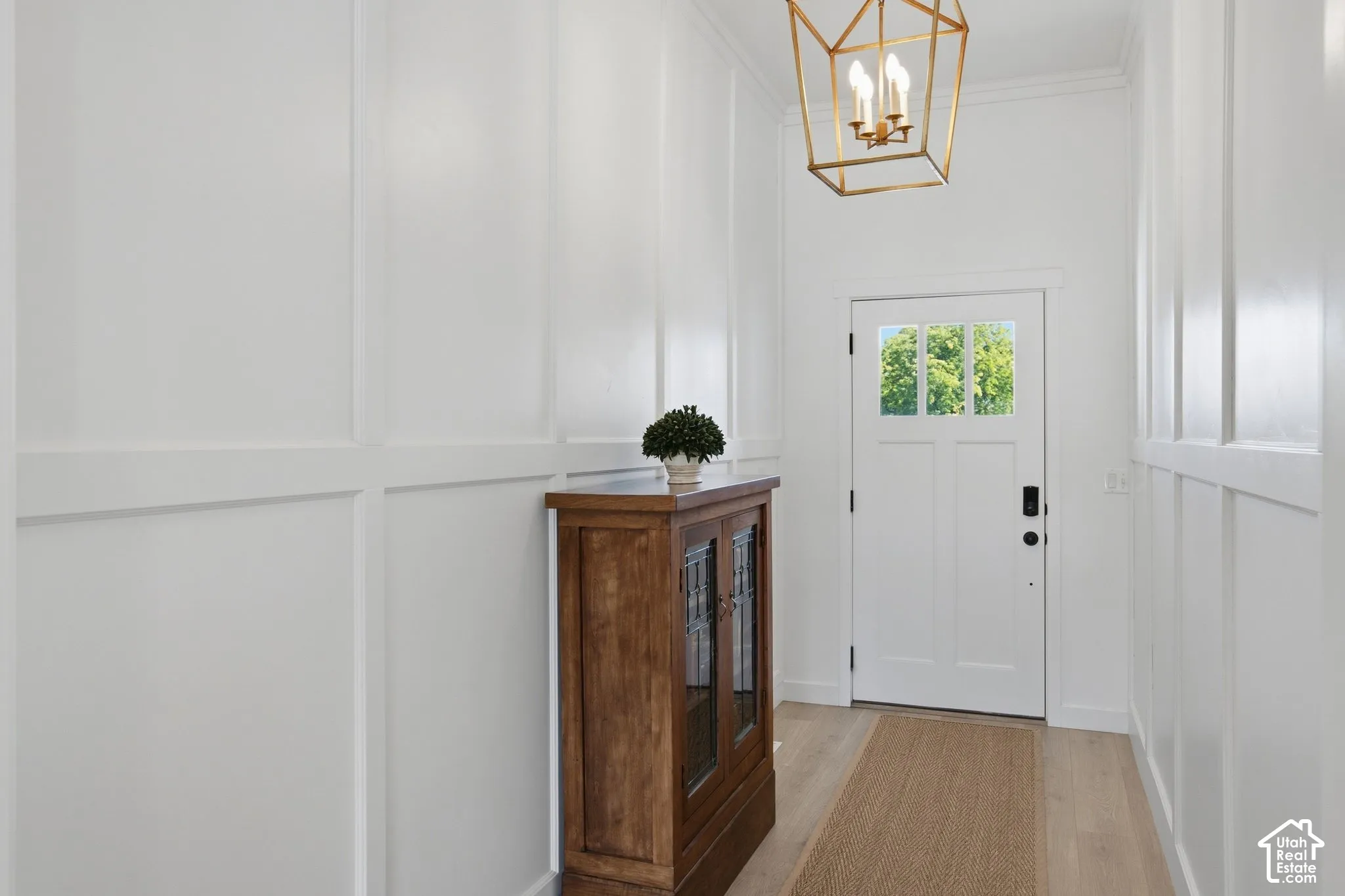 White paneled walls, light wood-finish flooring, and a white entry door with glass paneling