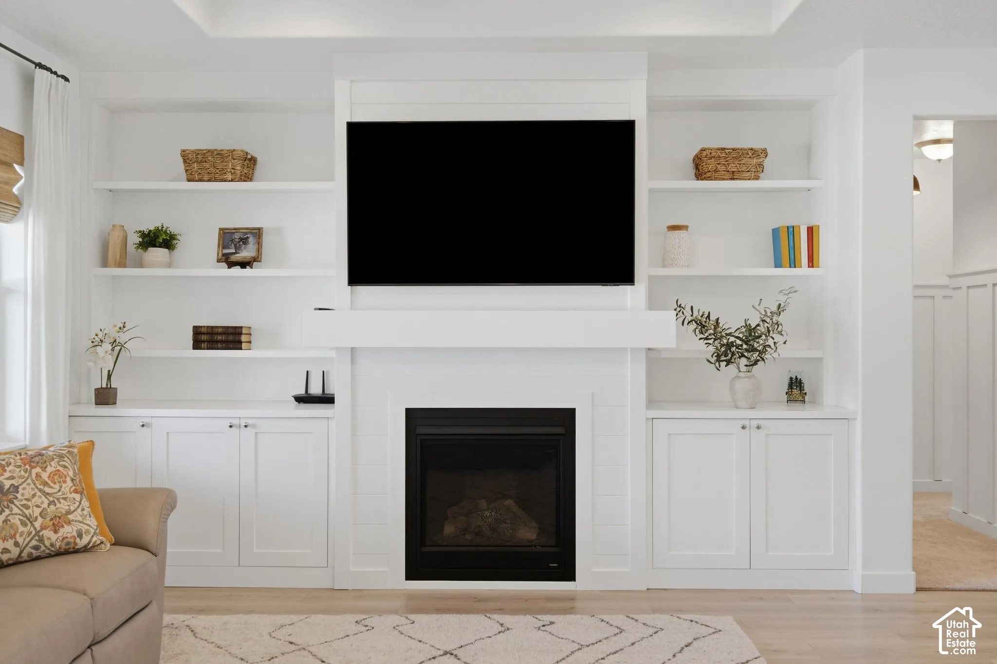 Built-in shelving and cabinetry framing a fireplace, with a wood-finish flooring