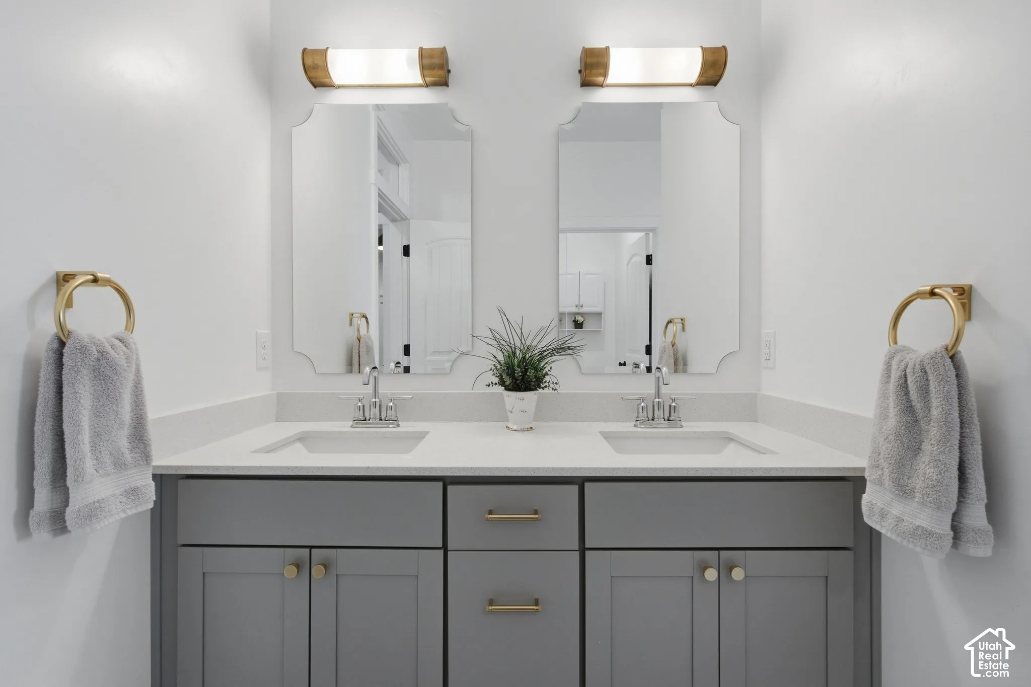 Dual vanities featuring undermount sinks, gray cabinetry, and brass hardware