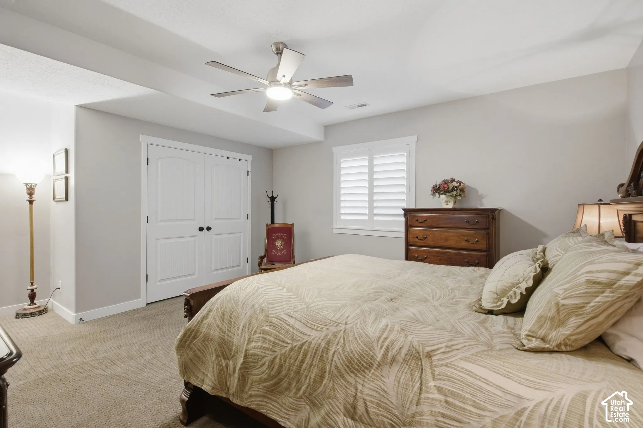 Carpeted flooring, recessed lighting, ceiling fan with integrated light, double-door closet with black hardware, and window with plantation shutters