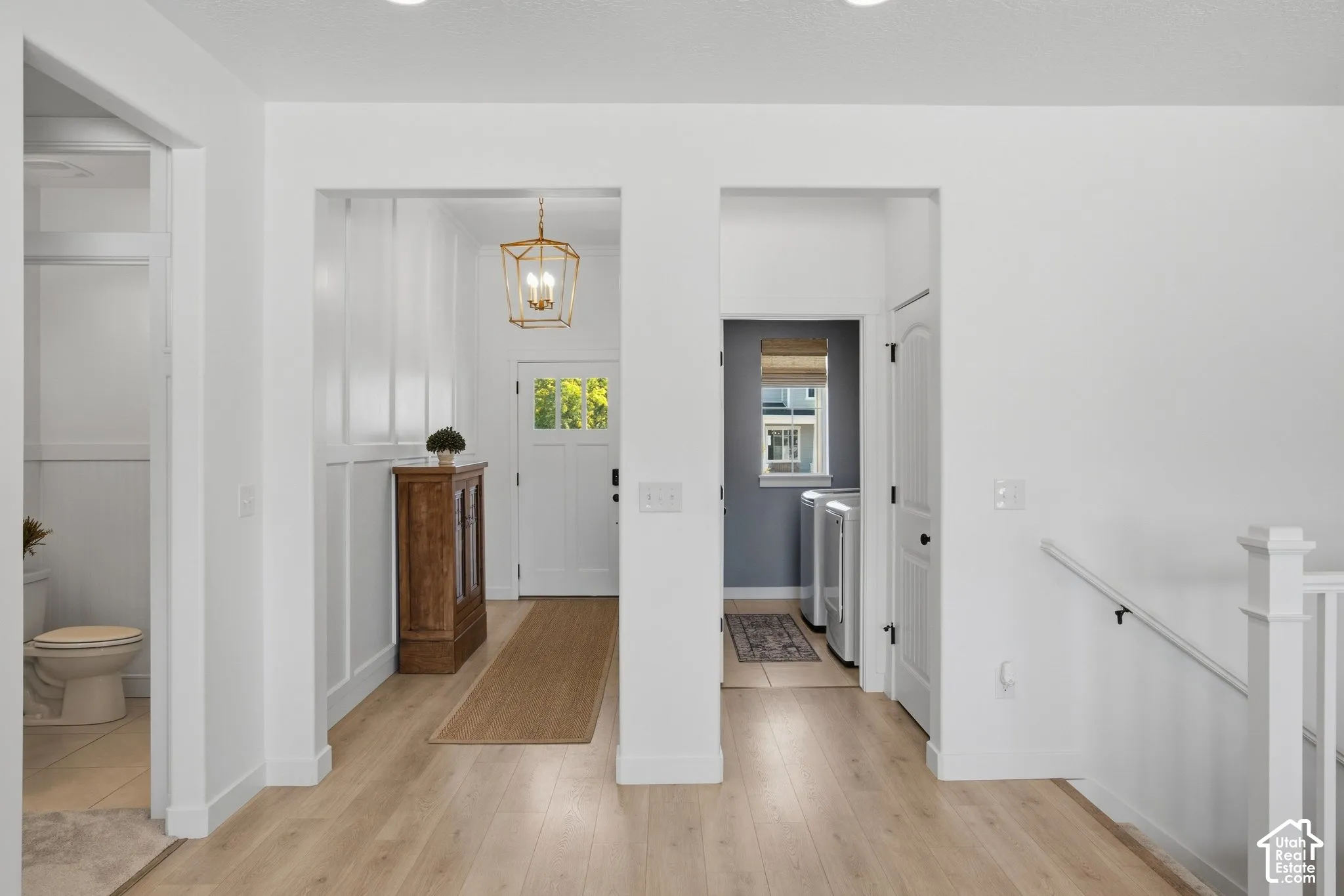Wood-finish flooring, white paneling, and a brass-finish chandelier