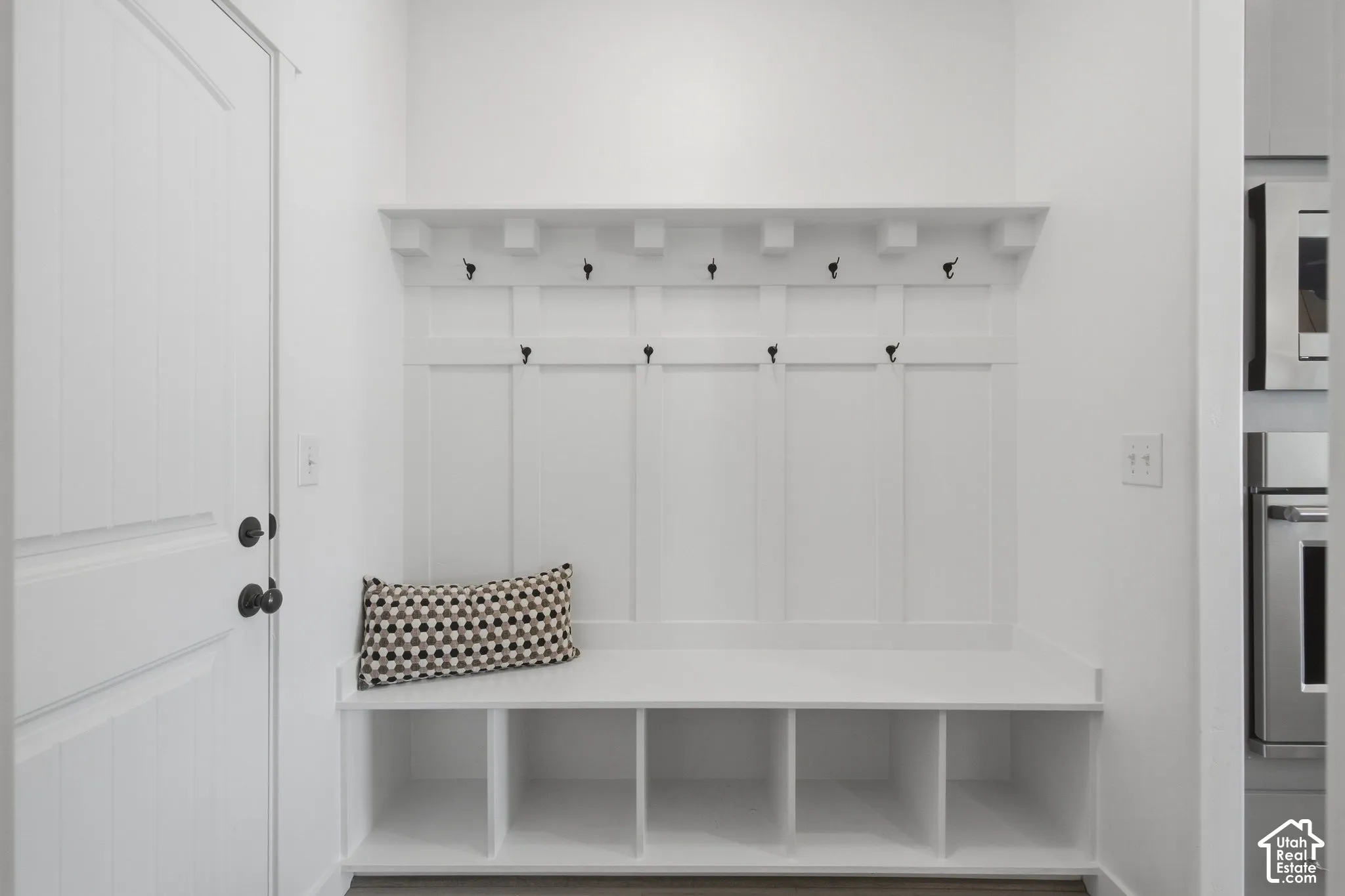 Built-in storage bench with cubbies, upper hooks, and a display shelf