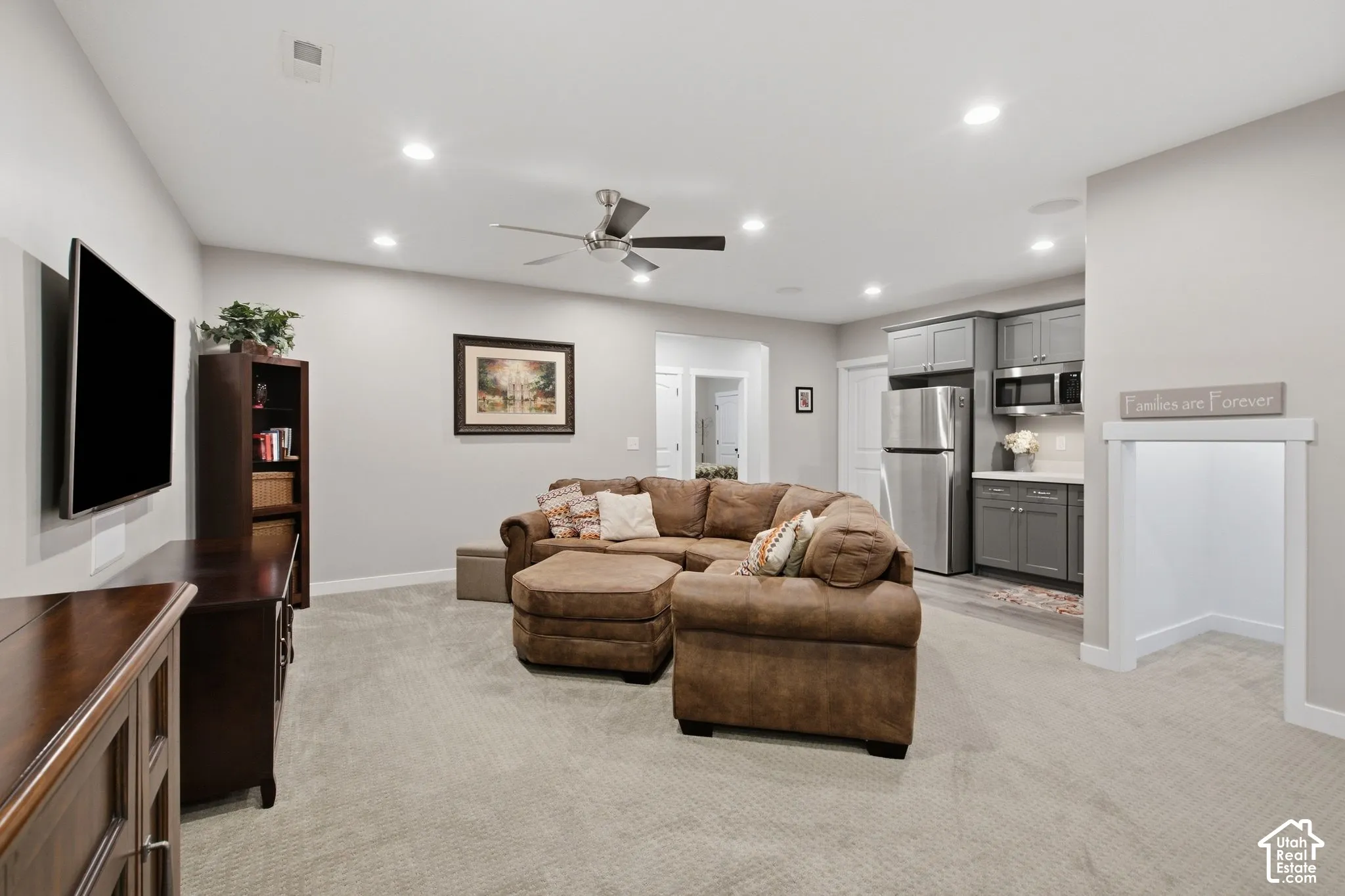 Recessed lighting, ceiling fan, and carpeted flooring in open-concept space with built-in cabinetry and stainless steel appliances